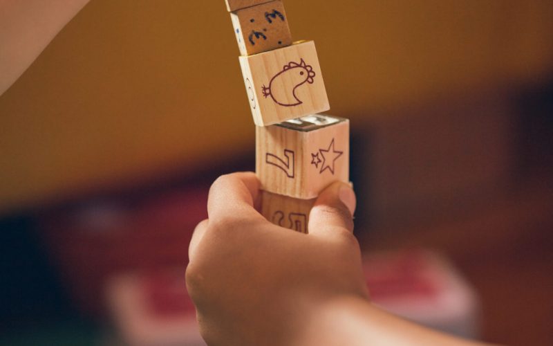 A vertical shot of a child and an adult playing with educational wooden cubes on the floor